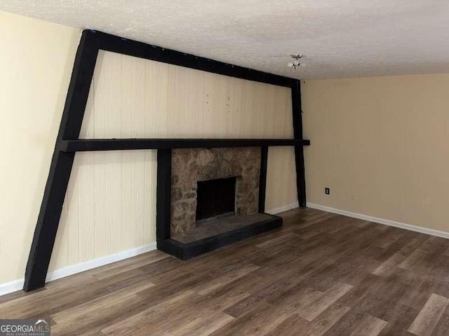 unfurnished living room with wood-type flooring, a stone fireplace, and a textured ceiling