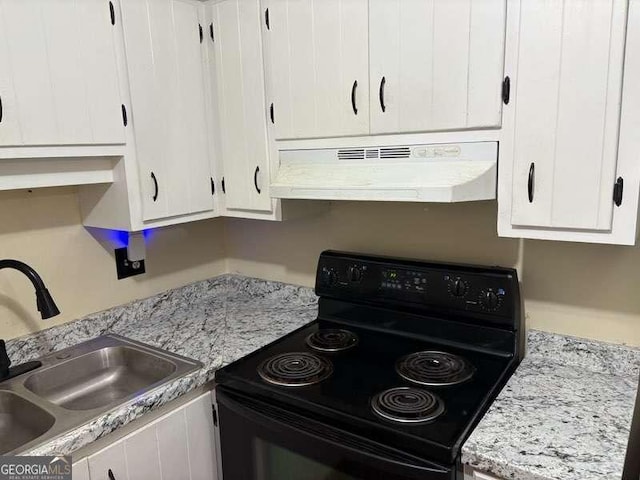 kitchen with light stone counters, black range with electric stovetop, sink, and white cabinets