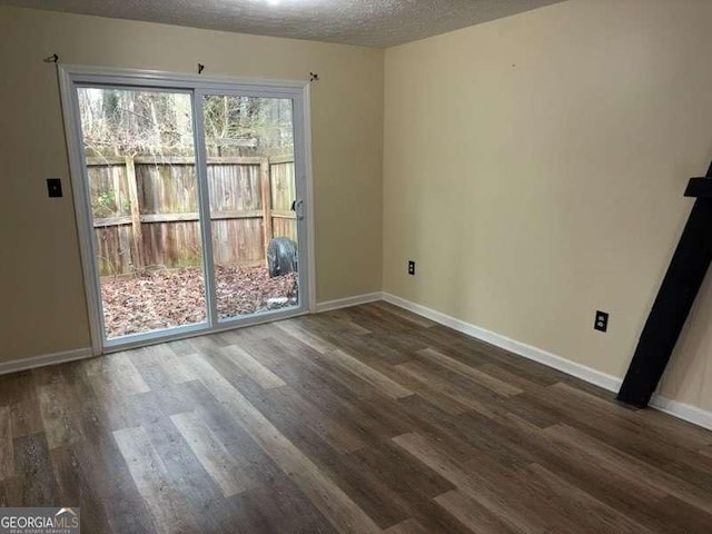 unfurnished room with dark wood-type flooring and a textured ceiling