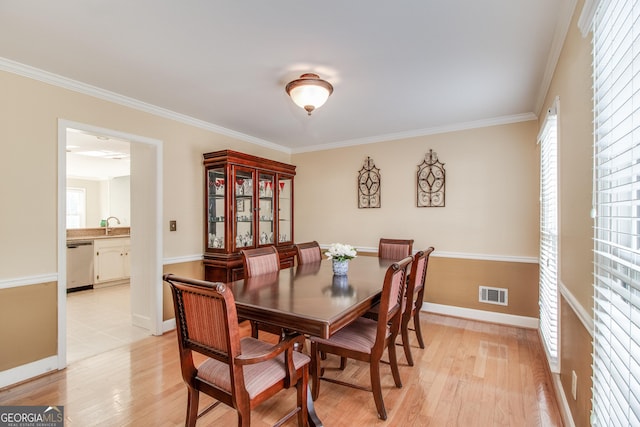 dining room featuring sink, ornamental molding, and light hardwood / wood-style floors