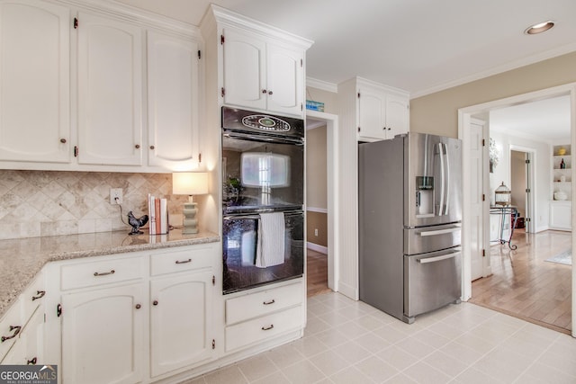 kitchen with white cabinets, black double oven, ornamental molding, and stainless steel fridge with ice dispenser