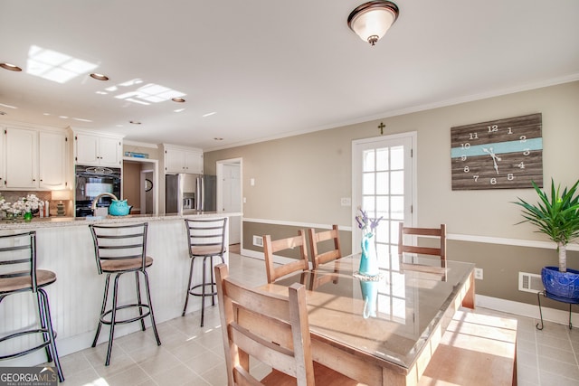 tiled dining room featuring crown molding