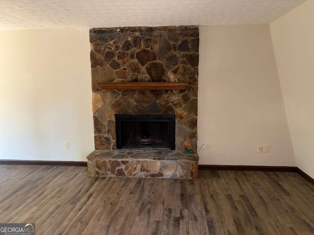 unfurnished living room with dark hardwood / wood-style floors, a textured ceiling, and a fireplace