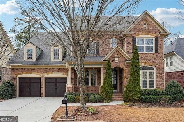 view of front of home featuring an attached garage, concrete driveway, and brick siding