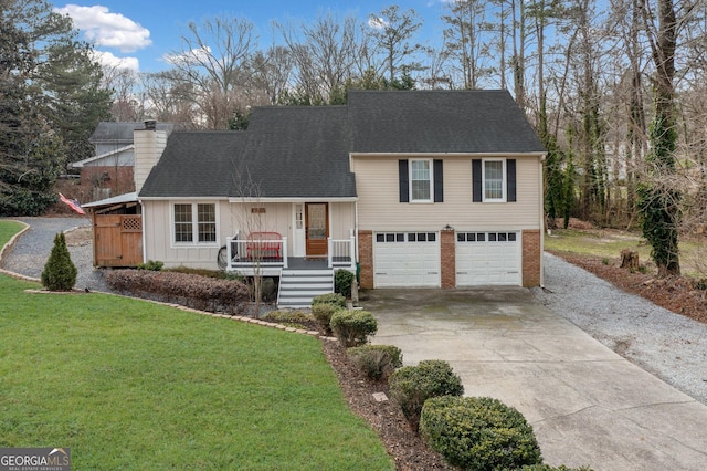 tri-level home featuring brick siding, a chimney, a front yard, a garage, and driveway