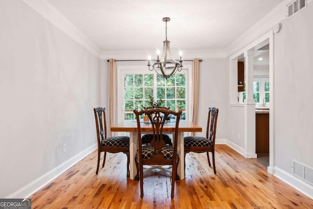 dining room with baseboards, visible vents, an inviting chandelier, crown molding, and light wood-type flooring