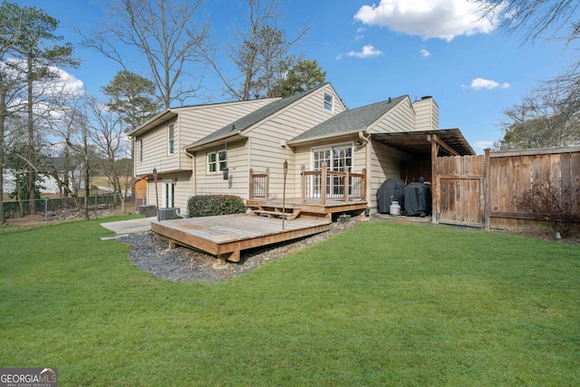 rear view of property with a fenced backyard, a chimney, a lawn, and a wooden deck