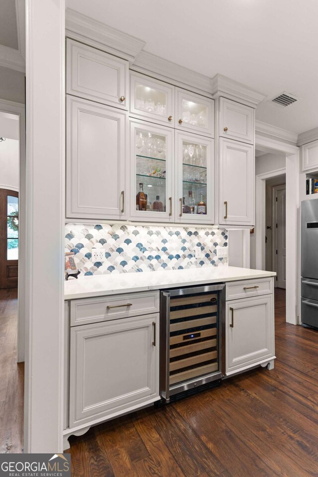 bar with dark wood finished floors, freestanding refrigerator, and beverage cooler
