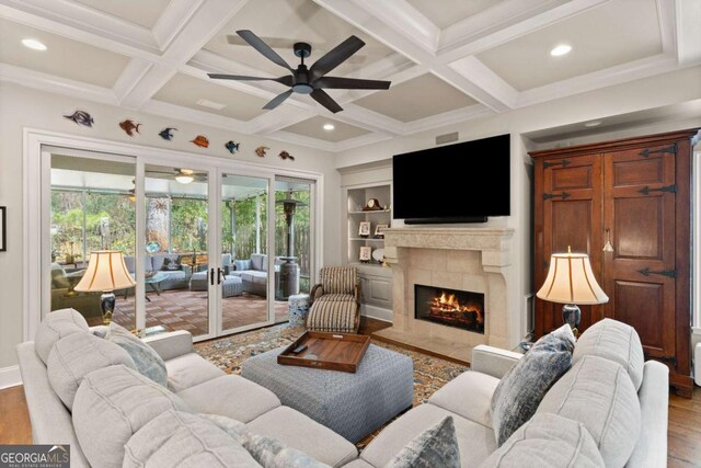 living room with a fireplace, beamed ceiling, a ceiling fan, and wood finished floors