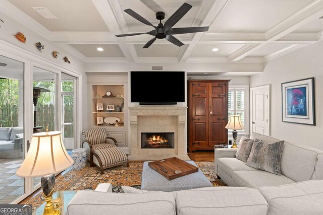 living room with a tile fireplace, beam ceiling, visible vents, and a wealth of natural light
