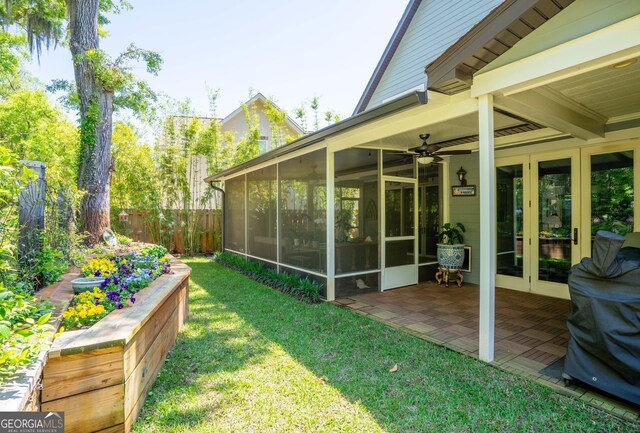 view of yard featuring french doors, fence, a patio, and a sunroom