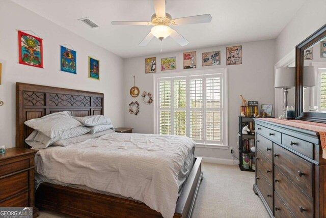 bedroom featuring visible vents, light colored carpet, baseboards, and ceiling fan