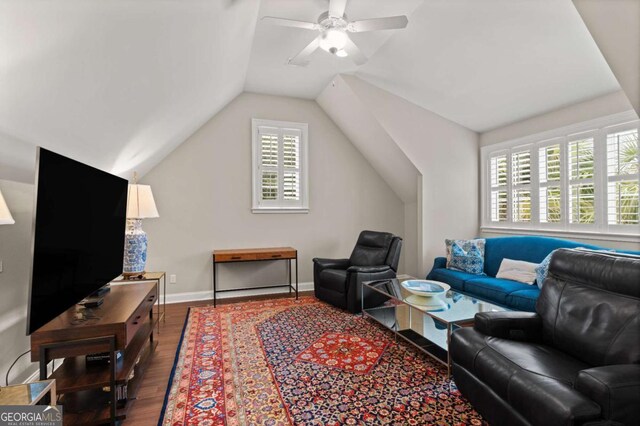 living area with baseboards, a ceiling fan, vaulted ceiling, and wood finished floors