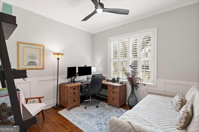 office space with crown molding, a decorative wall, ceiling fan, wood finished floors, and wainscoting