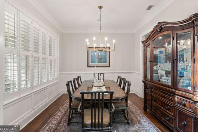 dining space featuring dark wood-type flooring, visible vents, an inviting chandelier, and crown molding