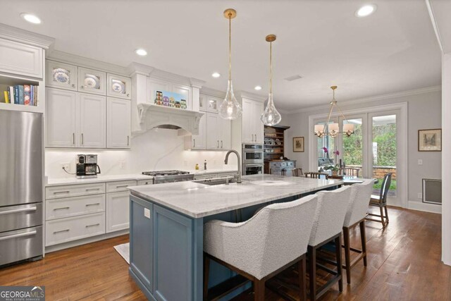 kitchen with ornamental molding, white cabinets, a kitchen bar, stainless steel appliances, and a sink