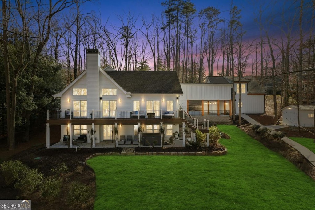 back of property featuring a yard, a wooden deck, and a patio