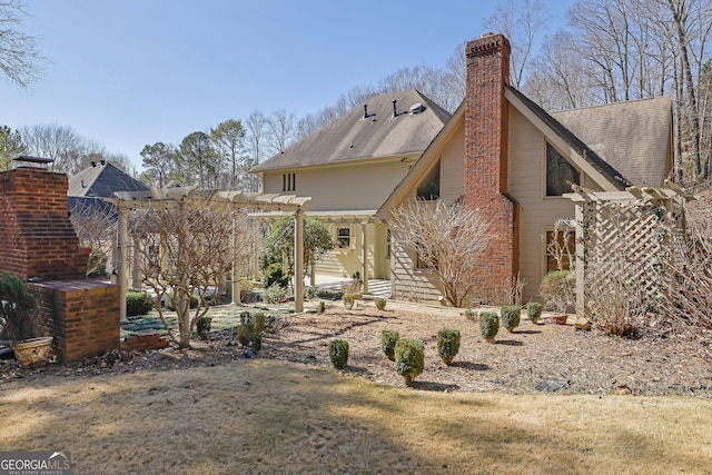 back of house with a shingled roof, a chimney, and a pergola