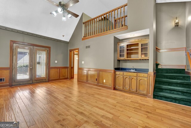 unfurnished dining area with light wood-style flooring, an inviting chandelier, crown molding, a textured ceiling, and a decorative wall