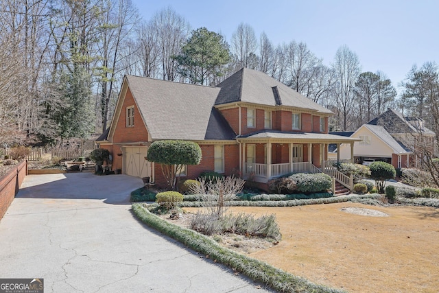 view of front facade with brick siding, a porch, a shingled roof, an attached garage, and driveway