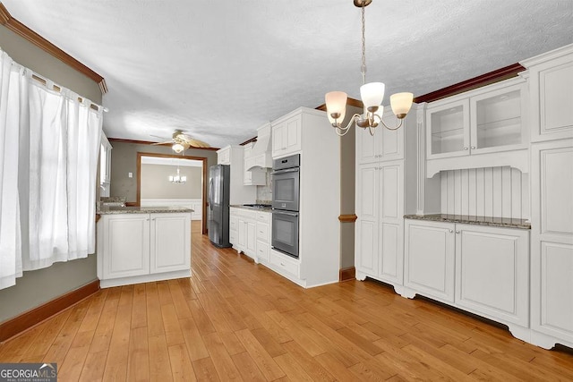 kitchen with white cabinets, appliances with stainless steel finishes, decorative light fixtures, light wood-type flooring, and ceiling fan with notable chandelier