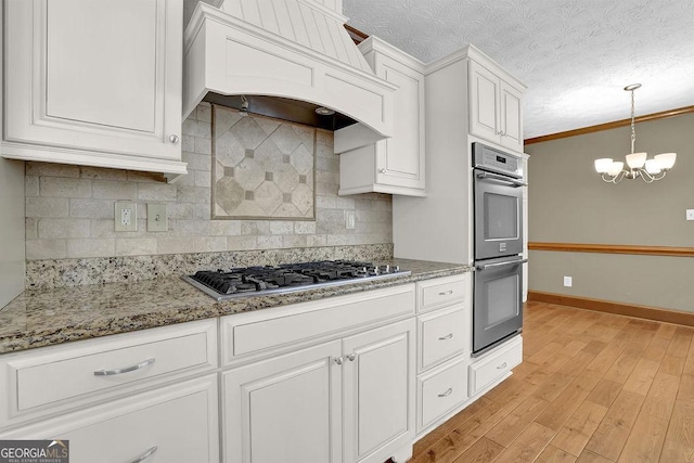 kitchen with stainless steel appliances, premium range hood, white cabinetry, and crown molding