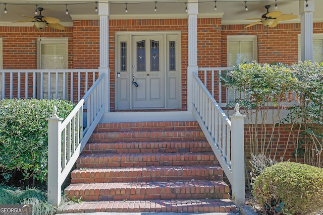 doorway to property with covered porch, brick siding, and a ceiling fan