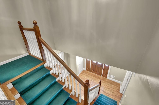 stairway with visible vents, baseboards, and wood finished floors