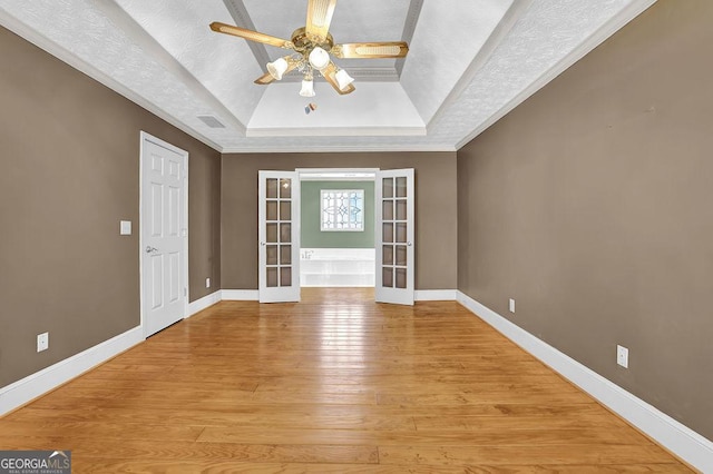 foyer entrance with french doors, a raised ceiling, visible vents, light wood-style floors, and baseboards