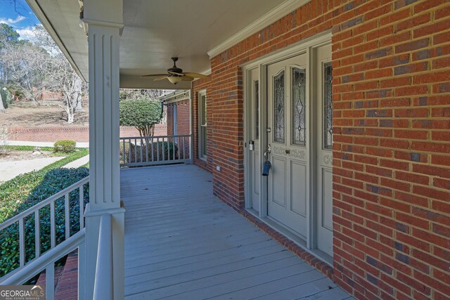 wooden terrace featuring covered porch and a ceiling fan