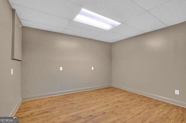 spare room with light wood-style flooring, baseboards, and a drop ceiling