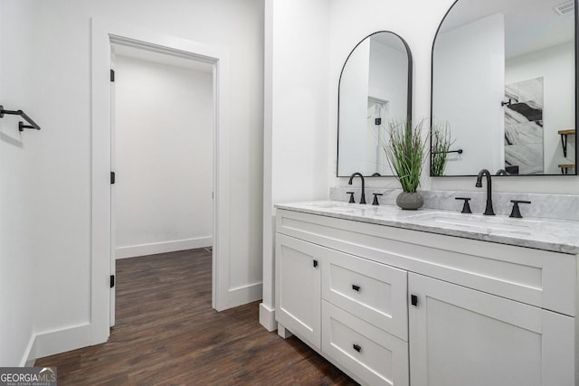 bathroom featuring double vanity, a sink, baseboards, and wood finished floors