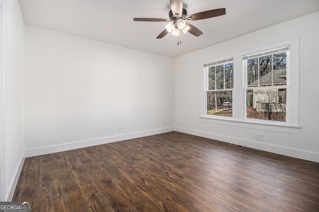 unfurnished room with baseboards, dark wood finished floors, and a ceiling fan