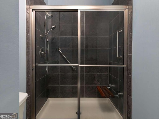 bathroom with a shower with door and toilet