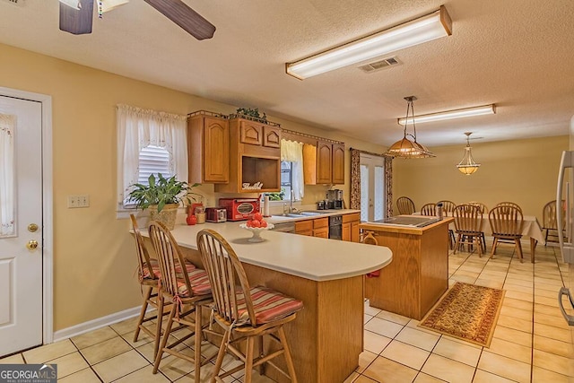 kitchen with pendant lighting, a breakfast bar area, a kitchen island, light tile patterned flooring, and kitchen peninsula