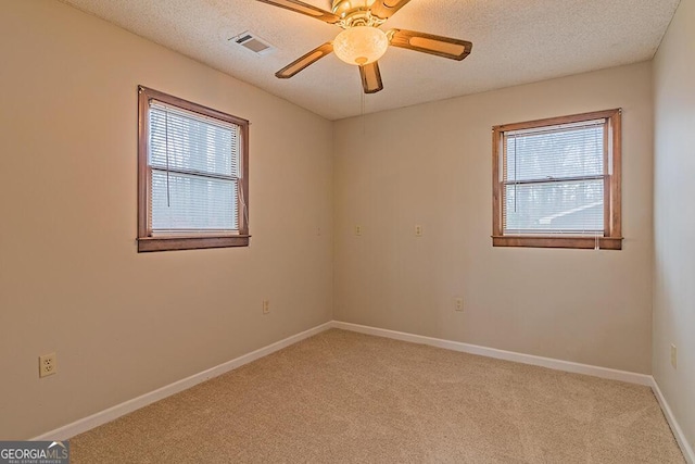 spare room featuring ceiling fan, light carpet, and a textured ceiling