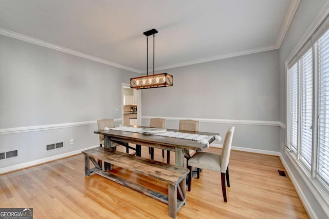 dining area featuring baseboards, ornamental molding, visible vents, and light wood-style floors