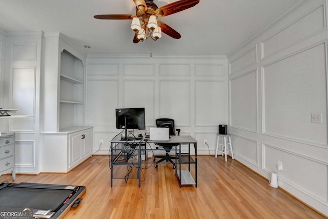 home office with light wood-style floors, built in features, a decorative wall, and crown molding