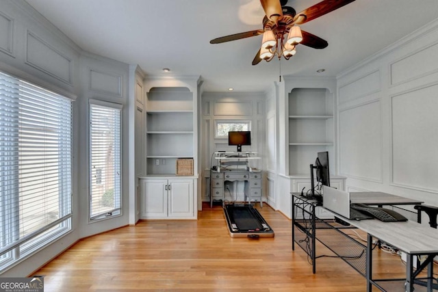 exercise area with built in shelves, a decorative wall, light wood-style flooring, and ornamental molding