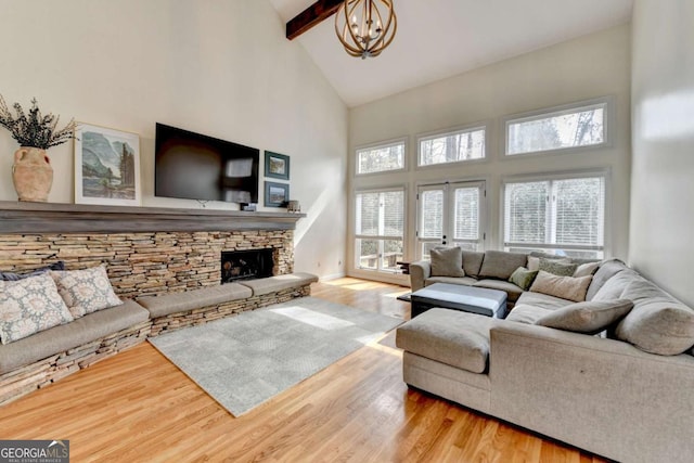 living area with beamed ceiling, a fireplace, and light wood-style flooring