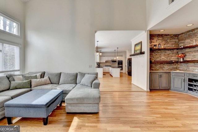 living area featuring light wood-type flooring and a towering ceiling