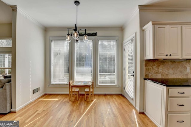 unfurnished dining area with light wood finished floors, an inviting chandelier, visible vents, and crown molding