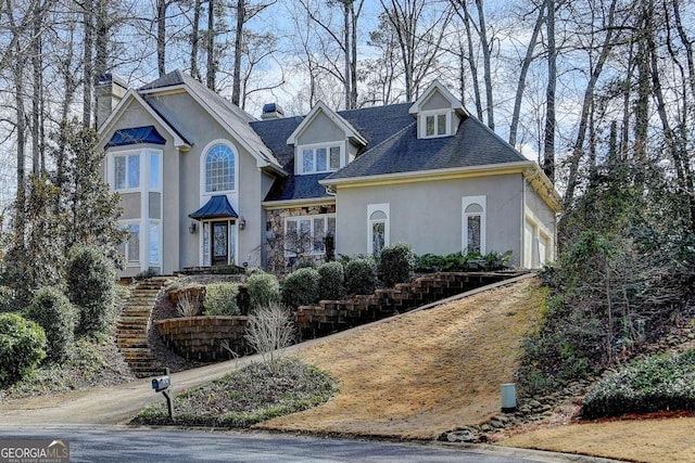 view of front facade featuring stone siding, a chimney, and stucco siding