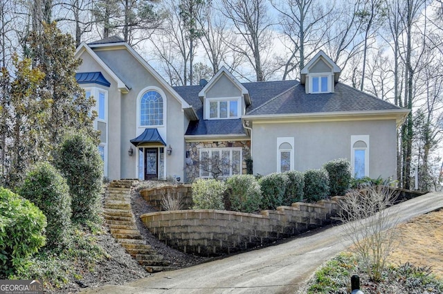 traditional-style home featuring metal roof, stone siding, roof with shingles, stucco siding, and a standing seam roof