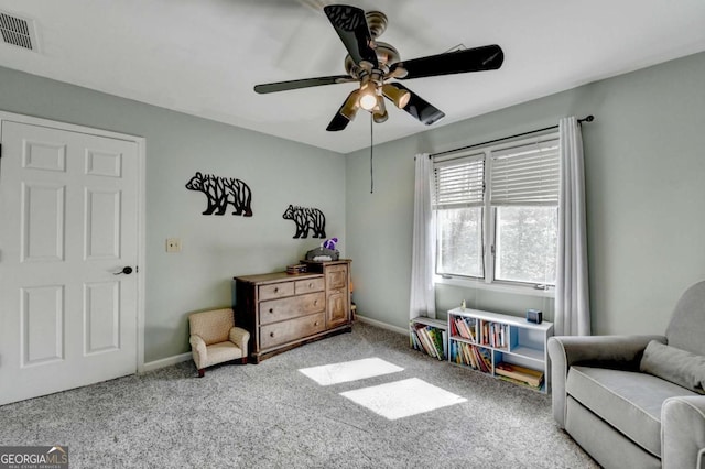 living area featuring baseboards, visible vents, ceiling fan, and light colored carpet