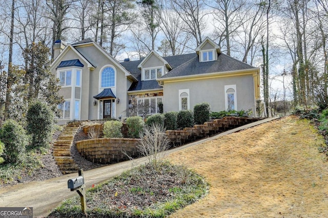 view of front of property featuring metal roof, stairway, stucco siding, a standing seam roof, and a chimney