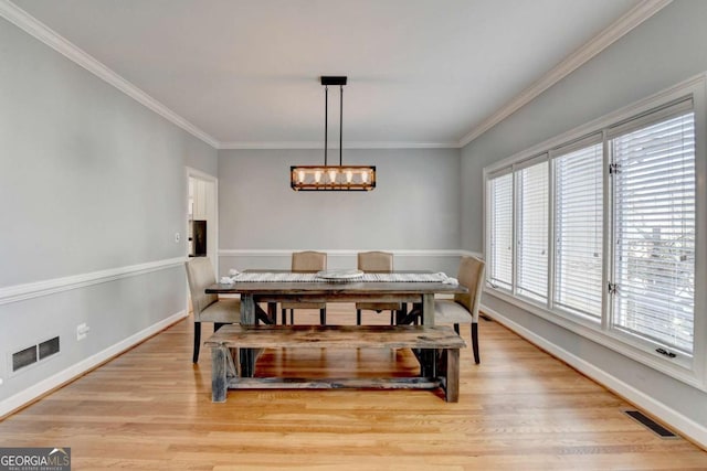 dining room featuring baseboards, ornamental molding, visible vents, and light wood-style floors