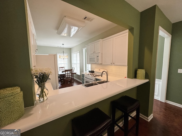 kitchen with pendant lighting, visible vents, white cabinetry, a sink, and white appliances