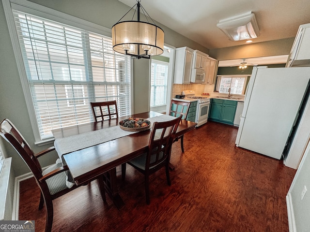 dining space with ceiling fan with notable chandelier and dark wood-style flooring