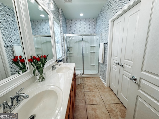 bathroom featuring wallpapered walls, a shower stall, a sink, and tile patterned floors